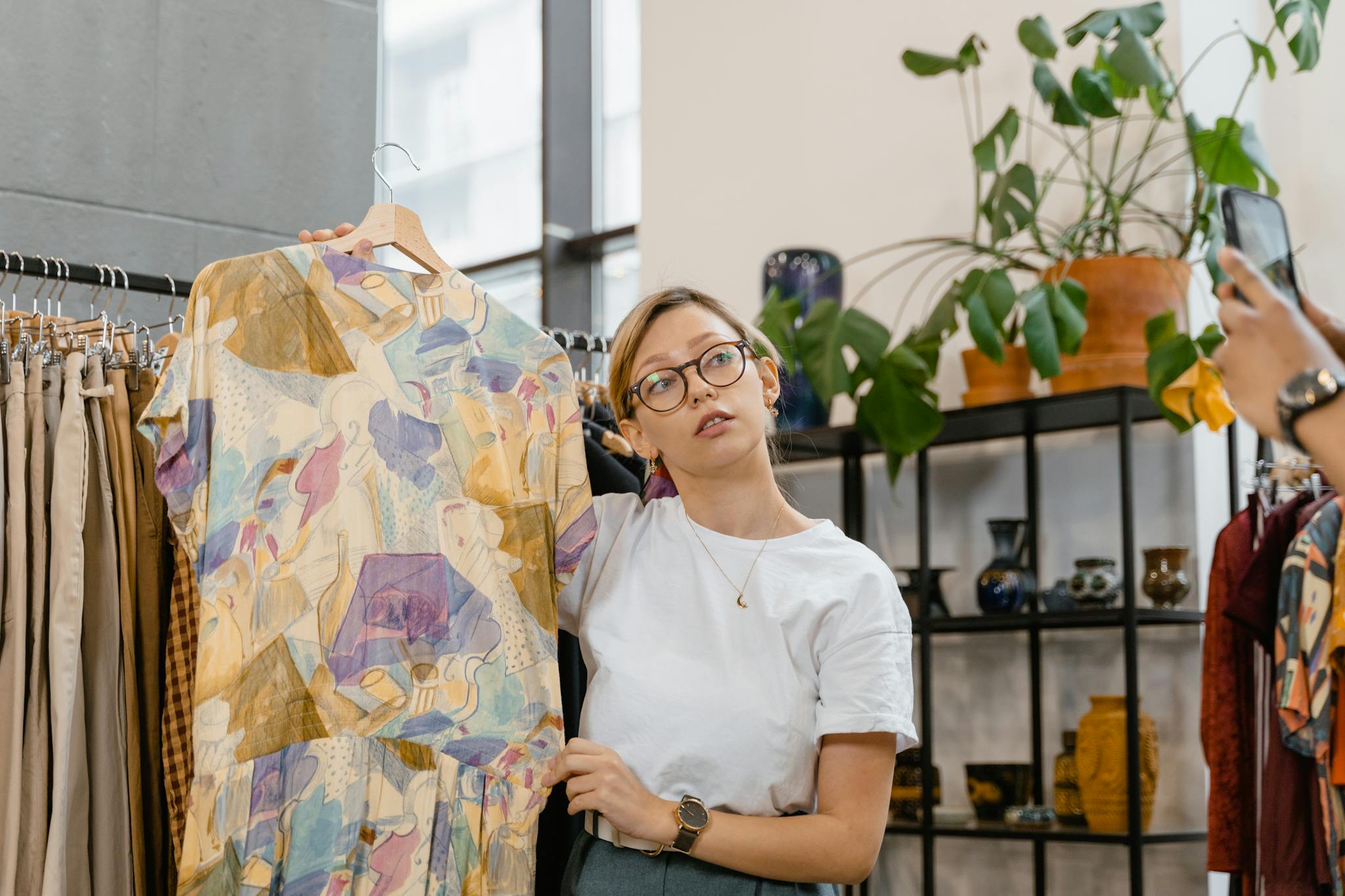 A woman showcasing a colorful dress in a stylish boutique setting, ideal for online selling.
