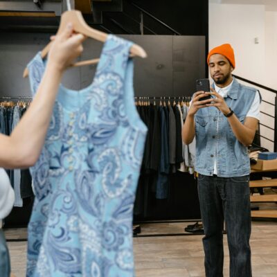 A young man photographs a dress in a boutique, focusing on fashion trends.
