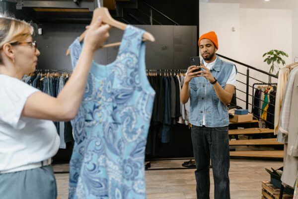 A young man photographs a dress in a boutique, focusing on fashion trends.
