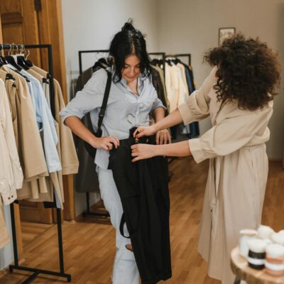 Fashion shop interior with customer and saleswoman interacting over clothes shopping.