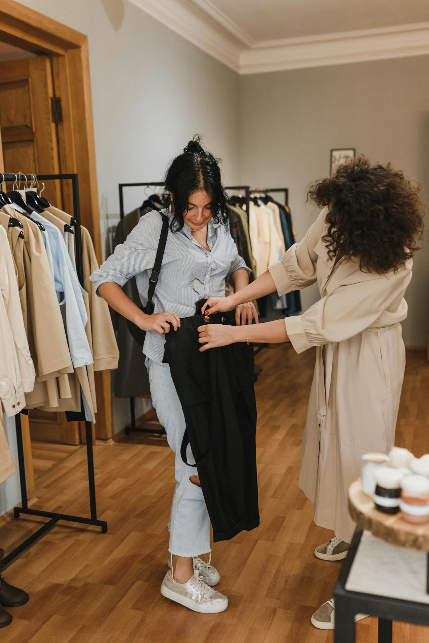 Fashion shop interior with customer and saleswoman interacting over clothes shopping.